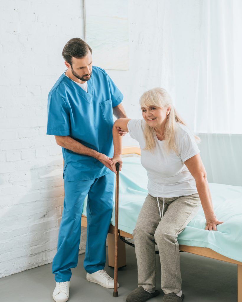 male-nurse-helping-senior-woman-with-walking-stick.jpg